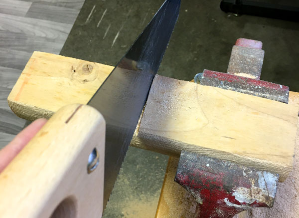 Cutting a piece of wood in half with a bench vice